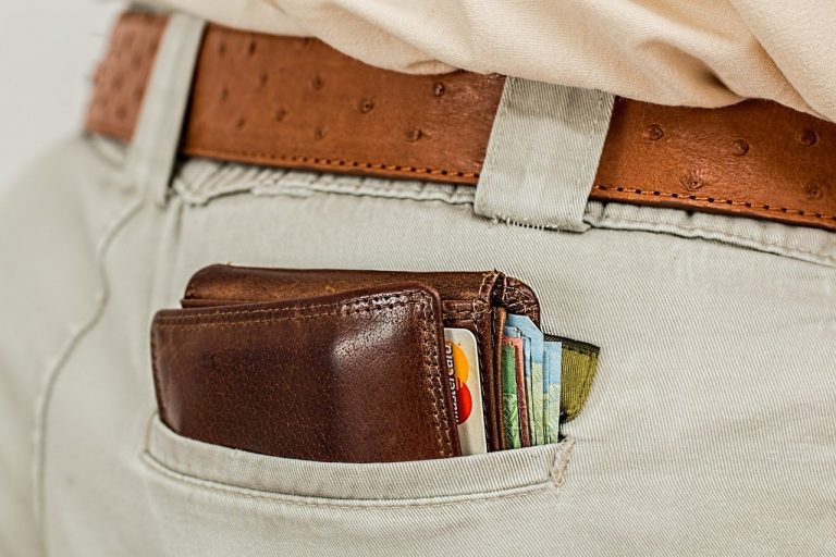 Wallet filled with credit cards and money hanging out of man's back pocket