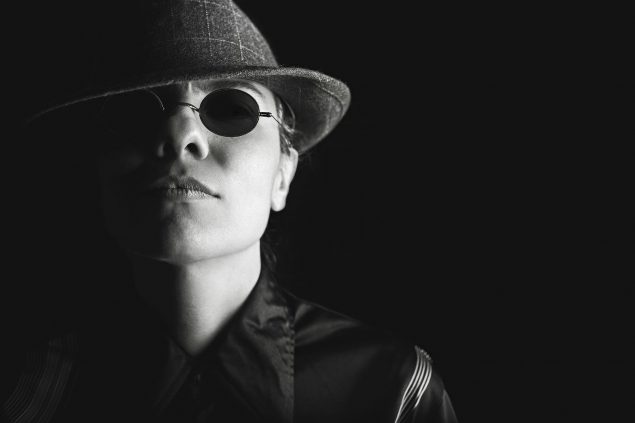 Black and white photo of a man wearing sunglasses and a hat, looking suspicious