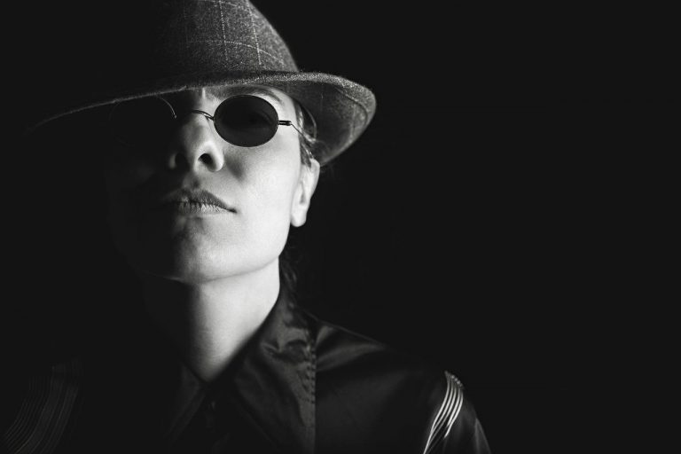 Black and white photo of a man wearing sunglasses and a hat, looking suspicious