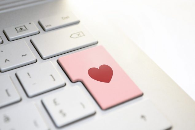 Laptop keyboard with a pink button and a red heart.