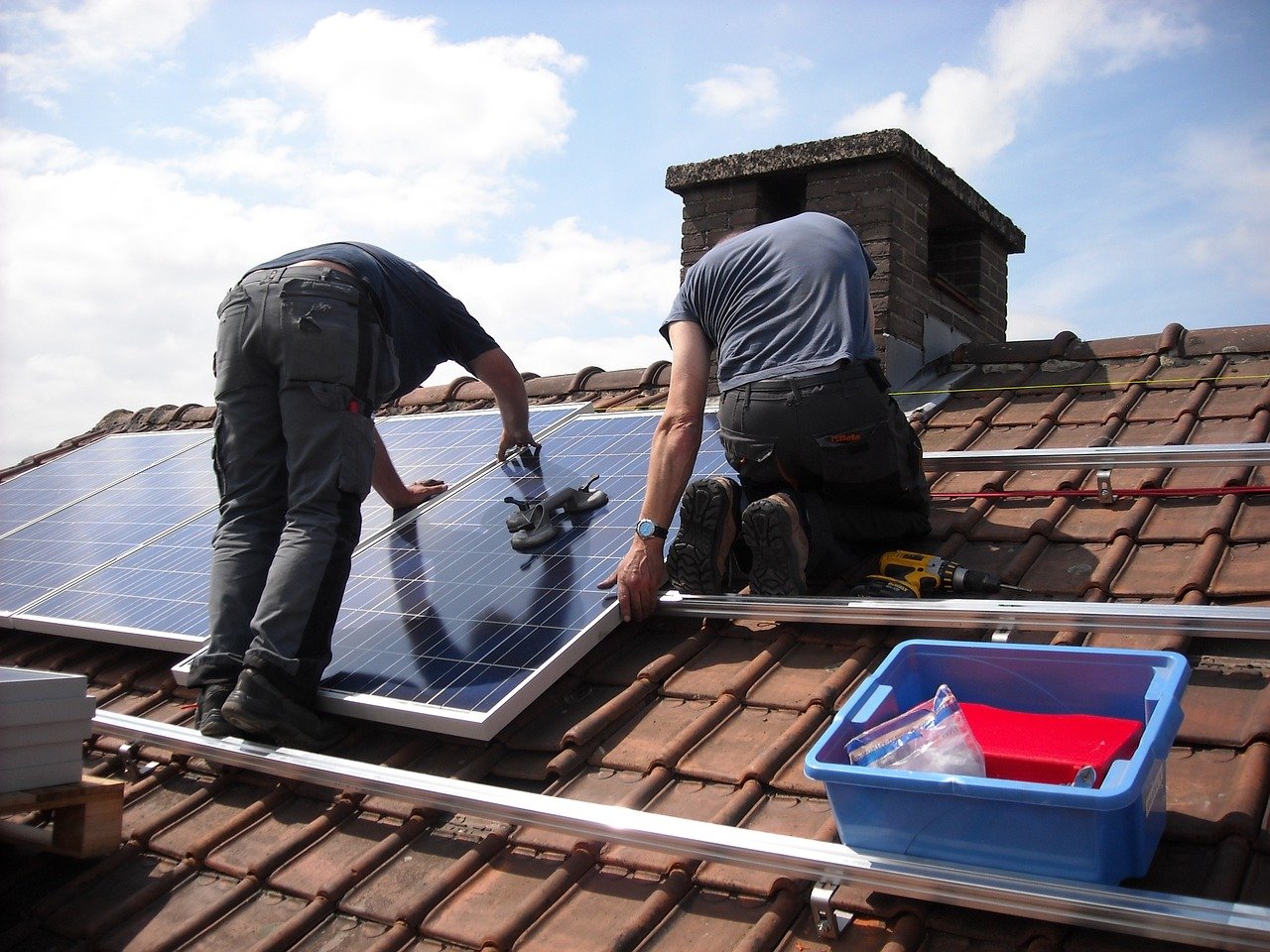 Workers installing solar energy panels on a roof.
