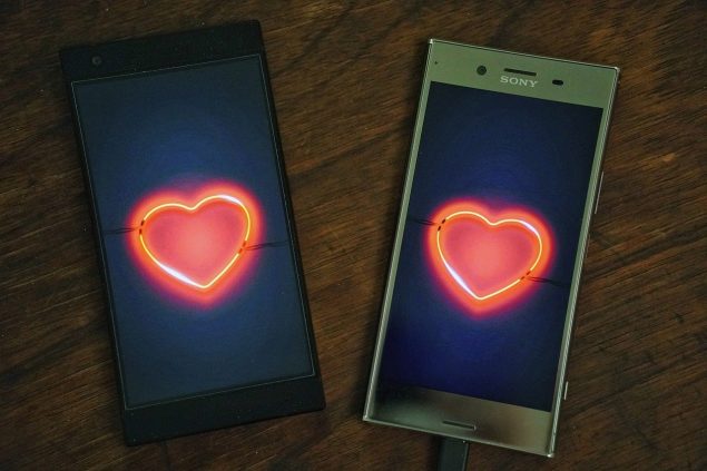 Two cell phones with hearts on the screens.
