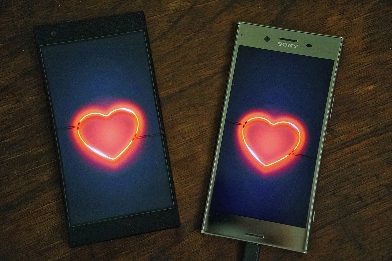 Two cell phones with hearts on the screens.
