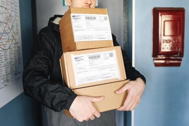 Man holding three packages outside front door