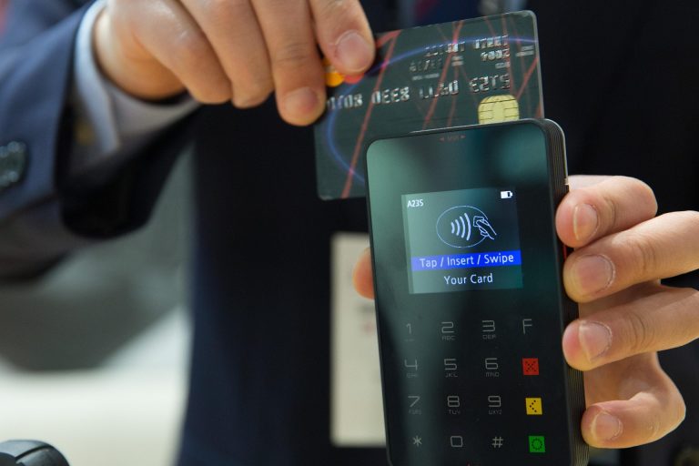 Man tapping a credit card to pay on a credit card machine.